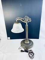 Full view of the decorative lamp showing the metal base, arm, and white glass shade with swirl pattern.