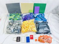 Full view of all bags of Mega Bloks with base plates and accessory pieces like doors and windows laid out.