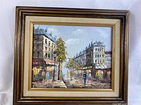 Front view of the framed oil painting depicting a Paris street scene with buildings, people, and trees, signed by Henry Rogers