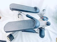 Full view of the Slazenger stepper machine showing black foot pedals, hydraulic resistance cylinders, and LED display with control button.