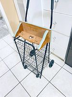 Photo of black folding grocery cart with wire body, wooden handle, and wheels