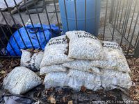 Stack of unopened bags of 1/2" white marble decorative garden stones, showing quantity and condition.