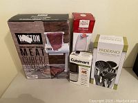 Photo showing all 4 boxed kitchen appliances : Weston Meat Cubers/Tenderizer, Cuisinart Spice and Nut Grinder, Paderno Utensil Set, Bon Appetit Can Opener.
