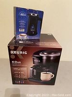 Two boxed items stacked: Keurig K-Duo Essentials coffee maker on bottom, Meseta Cremaccino milk frother on top