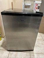 Front view of Midea mini fridge showing stainless steel body and black trim