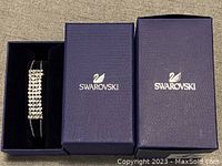 Photo of Swarovski bracelet displayed inside open navy blue branded box with two boxes side by side.