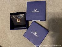 Swarovski necklace with pendant in open box alongside Swarovski boxes