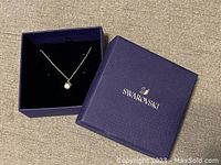 Swarovski necklace in open purple box with Swarovski logo inside box lid
