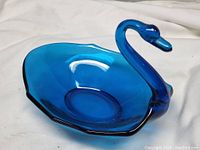 Blue glass swan-shaped dish photographed from an angled side view showing the shape and color.