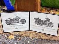 Photo of both framed Harley-Davidson motorcycle prints displayed outdoors on concrete with visible autumn leaves around