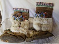 Pair of native Mohawk mukluks with beaded floral patterns, arctic hare fur cuffs, and worn deerskin base.