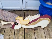 Folk art wooden angel decoration showing full side profile, displaying trumpet and wings.