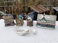 Overview of all five ceramic Christmas village houses with electrical cords and light switches visible.