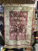 Front view of the small floral silk rug hanging vertically showing full pattern and fringes.