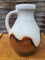 Front angle view of the white and brown glazed ceramic jug showing its robust handle and flowing brown accents on the body.