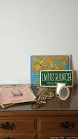 Front view of collection on wooden dresser showing Imus Ranch signed license plate, US map puzzle, music books, small frames, and small whistle instrument