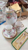 Photo of Noritake tea pot with two matching tea cups and a saucer, and a set of Irish Parian Donegal China spoons in presentation box