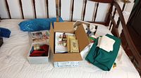 Wide view of sewing materials on bed including fabric, boxes of thread, buttons, and other notions.