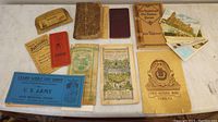 Collection of vintage books, booklets, postcards, and handouts arranged on table including First National Bank booklet, U.S. Army booklet, and various other ephemera.