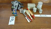 Vintage children's kitchen toy items including miniature tins labeled Bread, Flour, Sugar, Coffee, Cake, rolling pin, ladle, spatula, cookie cutters, and small vintage figurines in metal mesh bag.