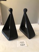 Pair of black cast metal stirrup shaped bookends shown from front angle on white cloth.