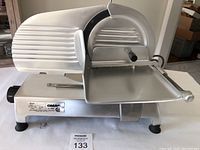 Front view of entire OMAS meat slicer showing blade guard, carriage and base