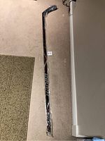 Full view of the Bauer hockey stick wrapped in plastic showing the product and packaging condition.