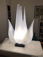 Frontal view of illuminated lamp showing full petal arrangement and base