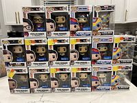 Front and side view of the 16 boxed Funko Pop figures showing variety including Ryan Howard and Phyllis Vance from The Office, Ski Harry Dunne from Dumb and Dumber, and others.
