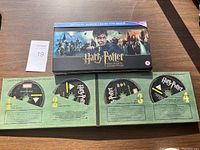 Photo of Harry Potter Hogwarts Collection box with four discs visible inside. Discs labeled with movie titles and disc numbers.