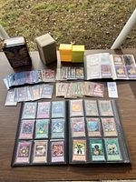 Photo of Yu-Gi-Oh! cards laid out on a table with binders, protective sleeves, and card boxes