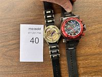 Two wristwatches side by side on a wooden surface, showing full bands and dials.