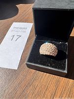 Ring in its box on a wooden surface with a MaxSold lot number card.