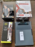 Four workout items displayed: SaunaFX Sauna Vest box, Performance Balance Ball box, Athletic Works Resistance Tube box, and a digital scale.