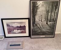 Photo showing three framed photos: large black and white Paris photo, large mountain landscape photo, small panoramic photo.