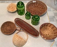 Photo from above showing three green glass hexagonal jars with lids and seven assorted woven wicker baskets in various shapes and sizes, sorted around them.