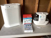 Photo showing the Honeywell air purifier, two filter boxes, and the Homedics humidifier with remote.
