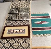Lot overview with metallic art pieces, woven textiles, and framed print arranged on table