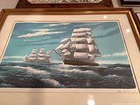 Framed lithograph featuring sailing ships on ocean waves, signed by artist Alex Packhany visible on bottom right.