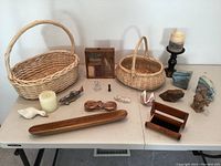 Photo showing the entire collection spread over two tables, including two woven baskets, wooden tray, various small figurines mostly neutral tones, candle holder with candle, and decorative items.