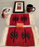 Overview of woven tapestries, ceramic tile, framed print, wooden bird, and mug.