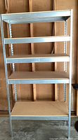 Front view of steel frame shelving unit with five pressed wood shelves.