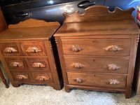 Full view of two vintage solid wood dressers side by side showing size difference and carved acorn handles