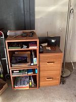 Two wood cube storage units, one wood short file cabinet, and various supplies on and around them