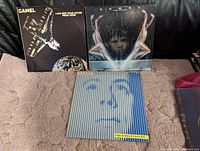 Front view of the three vintage Camel LP albums with original covers displayed side by side on a carpeted surface against a black background.