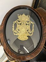 Front view of the oval framed Napoleonic French bronze armorial plaque behind convex glass, showing detailed bronze relief and dark polished wood frame with beading.