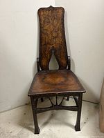 Front view of chair showing shield back and seat with pyrography floral motifs and stretcher.