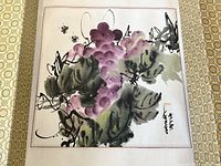 Close view of the watercolor painting showing grapes and leaves, with artist calligraphy and red stamp signature on the right.