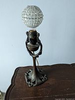 Front view of lamp unlit on wooden table showing globe shade and ornate metal base