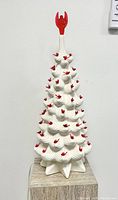 Front view of unlit tree with white ceramic branches and red topper